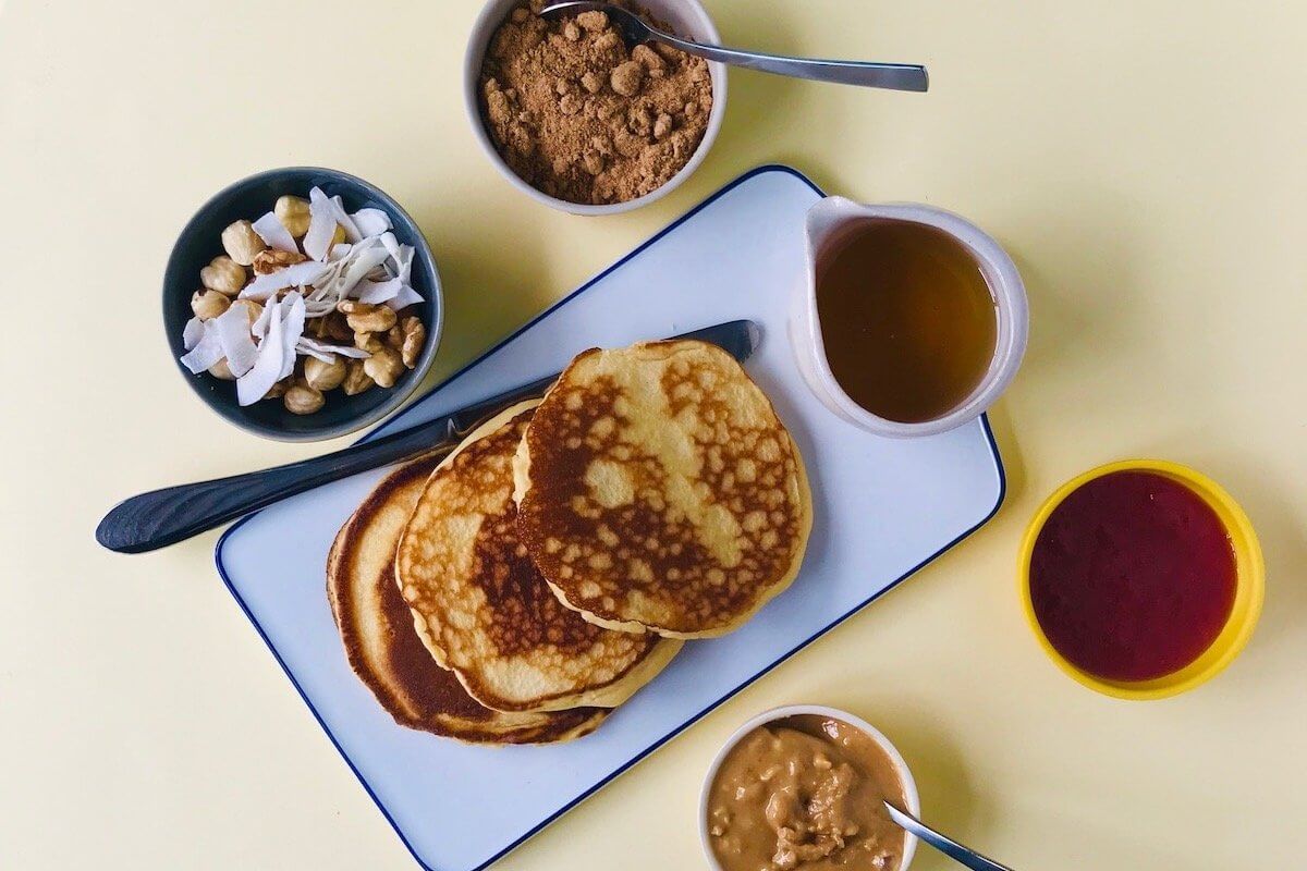 A pile of pikelets with crushed nuts and honey